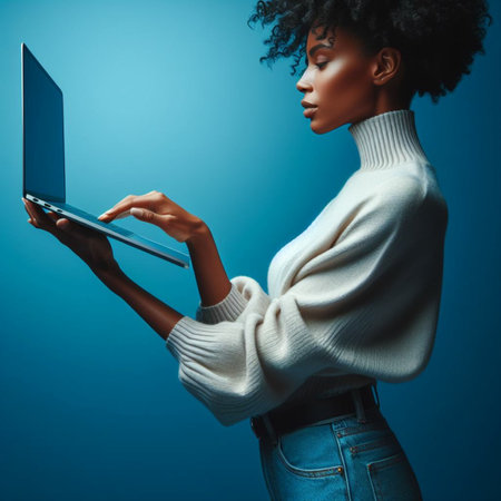 Young african american woman using laptop computer on blue background.の素材