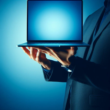 Close up of businessman hands holding laptop computer with blank screen on blue backgroundの素材