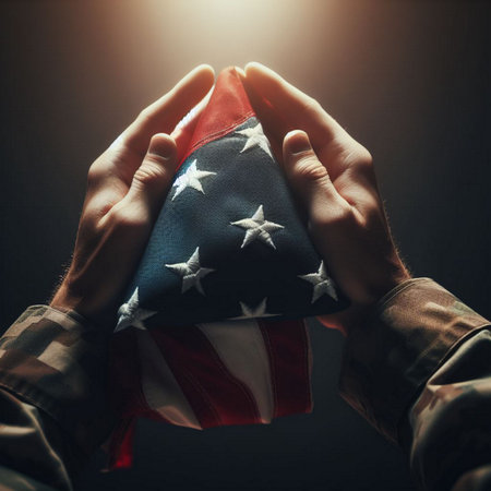 Close-up of man's hands holding American flag on dark backgroundの素材