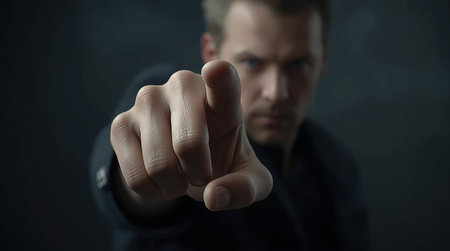 Portrait of a young man in a black suit pointing at the camera.の素材