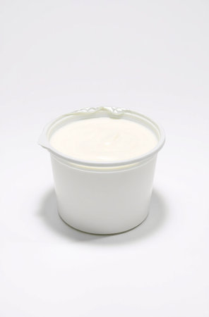 Yogurt in a white plastic container on a white background.の素材