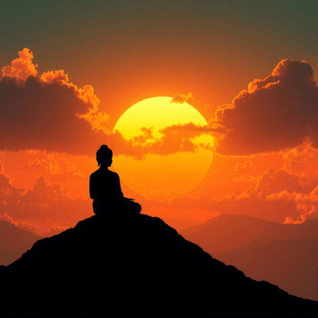 Silhouette of a man meditating on top of a mountain at sunsetの素材