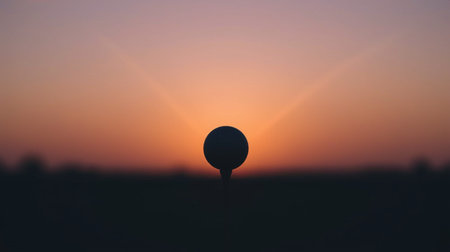 Golf ball on a tee in the field at sunset with sun raysの素材