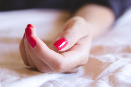 Female hand with red nails on a white background. On her nails red manicure.の写真素材