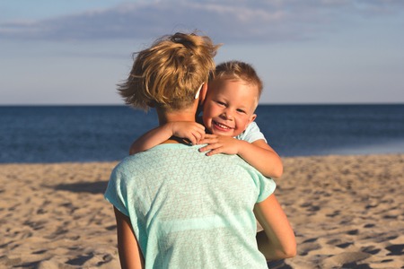Portrait of young mother with her little son playing on the beach near the seaの写真素材