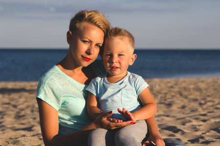 Portrait of young mother with her little son playing on the beach near the seaの写真素材