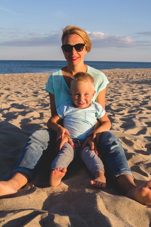 Portrait of young mother with her little son playing on the beach near the seaの写真素材