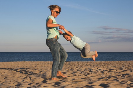 Portrait of young mother with her little son playing on the beach near the seaの写真素材