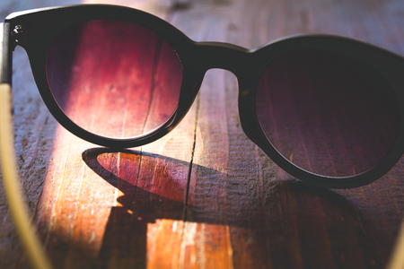 Sunglasses with shadow on wooden background. Close up. Toned image.の写真素材