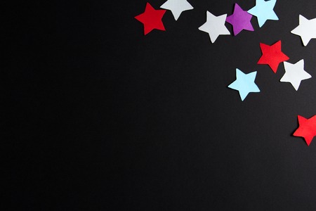 Paper stars of different colors on a black backgroundの写真素材