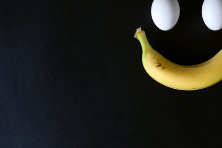 Smile from eggs and banana on black background, close upの写真素材