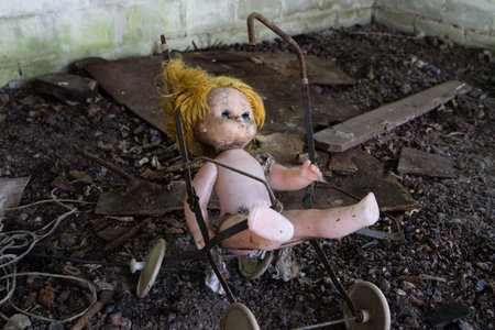 Old abandoned doll on a broken toy stroller at the abandoned houseの写真素材