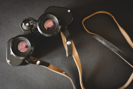 Old binoculars with strap on black background. Top viewの写真素材