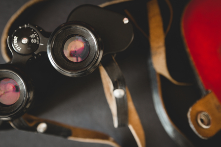 Old binoculars with strap and red case on black backgroundの写真素材
