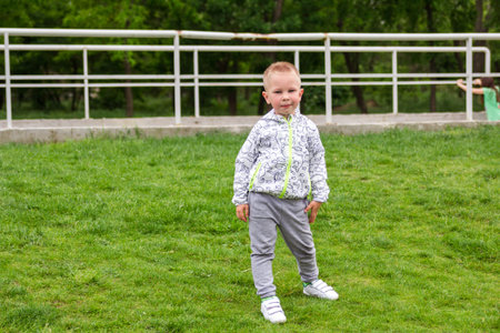 Portrait of cute boy snding on green field in the parkの写真素材