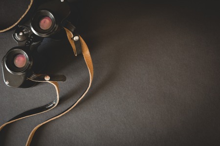 Old binoculars with strap on black background. Top viewの写真素材