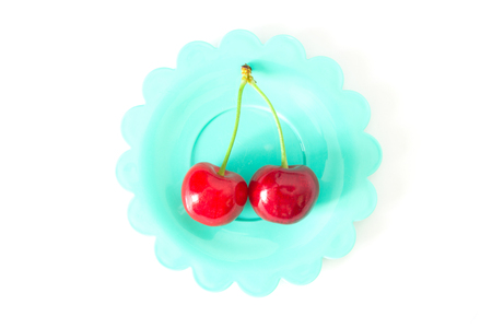 cherries on bright colored saucers isolated on whiteの写真素材