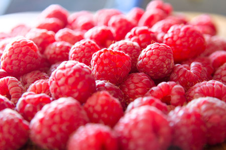 Ripe sweet raspberries in bowl on wooden table. Close up, top view, high resolution product
