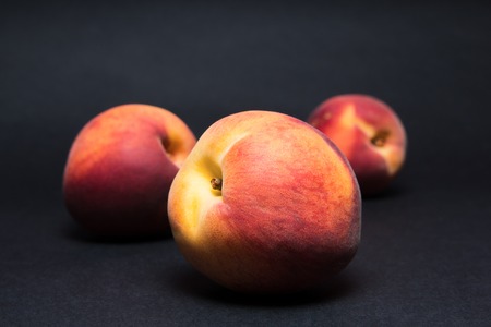 Close up shot of a fresh peach isolated on a black backgroundの写真素材