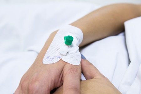 Injection cathetter in the hand of patient lying in the bedの写真素材