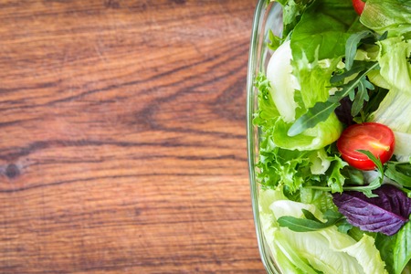 Green summer salad with cherry tomatos, basil on wooden boardの写真素材