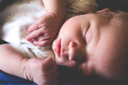A sweet one month old newborn baby boy is sleeping covered by blanket