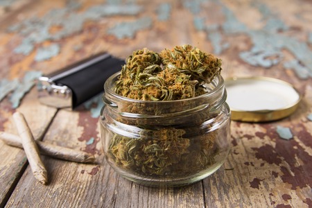 Marijuana buds in the glass pot on the rustic wooden tableの写真素材