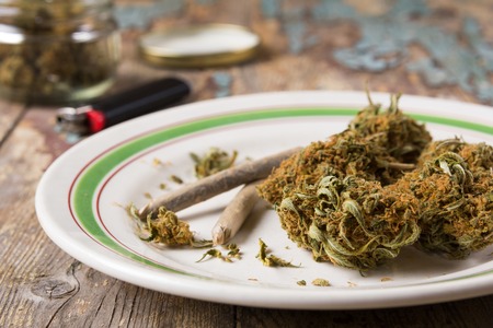 Marijuana buds and joints in the glass plate on the wooden rustic tableの写真素材