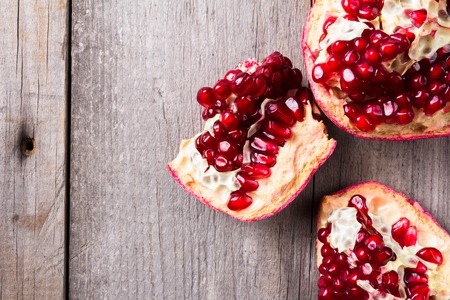 Broken red ripe juicy pomegranates on rustic wooden unpainted table Top viewの写真素材
