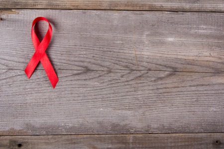 Red ribbon as symbol of aids awareness on gray wooden backgroundの写真素材