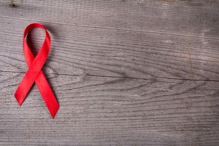Red ribbon as symbol of aids awareness on gray wooden backgroundの写真素材