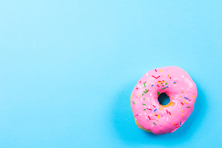 Pink round donut on blue background. Flat lay, top view.の写真素材