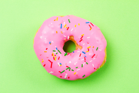 Pink round donut on green background. Flat lay, top view.の写真素材