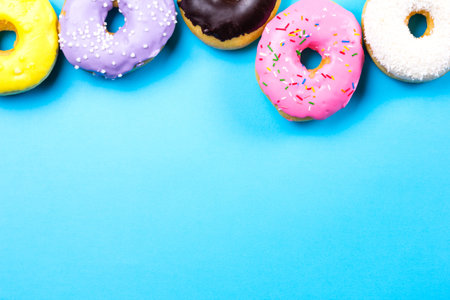 Colorful round donuts on blue background. Flat lay, top view.