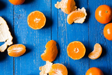 Whole, cutted and pilled mandarins on a blue painted wooden backgroundの写真素材