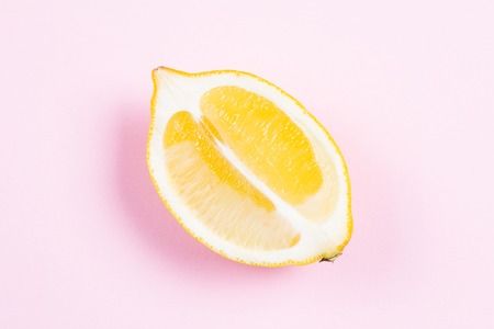 Whole and sliced lemon on pink backgroundの写真素材