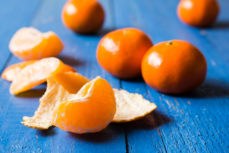 Whole, cutted and pilled mandarins on a blue painted wooden backgroundの写真素材