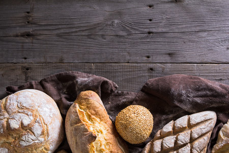 Several types of fresh bread lying on an old wooden tableの写真素材