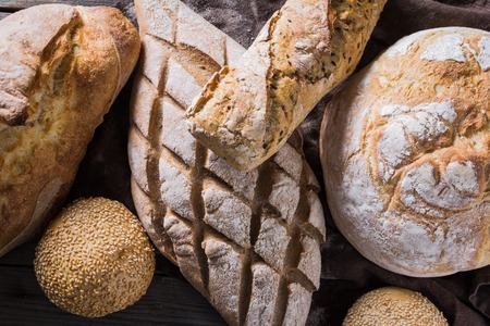 Several types of fresh bread lying on an old wooden tableの写真素材