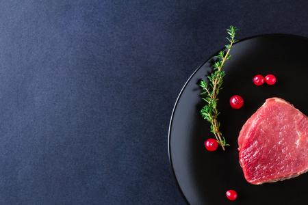 Raw meat on black plate and dark backgroundの写真素材