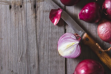 Red onion bulbs lying on an old wooden table. Above view still lifeの写真素材