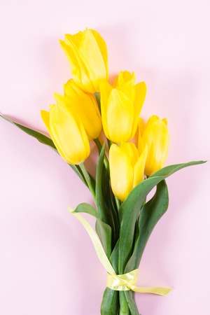 Bouquet of beautiful fresh yellow tulips on pink background. View from above photo. Space for textの写真素材