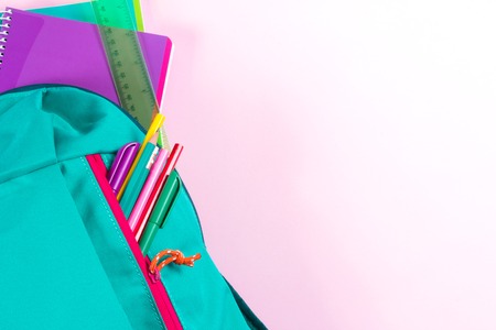 Backpack with school stationery and apple on pink backgroundの写真素材