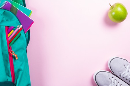 Backpack with school stationery and apple on pink backgroundの写真素材