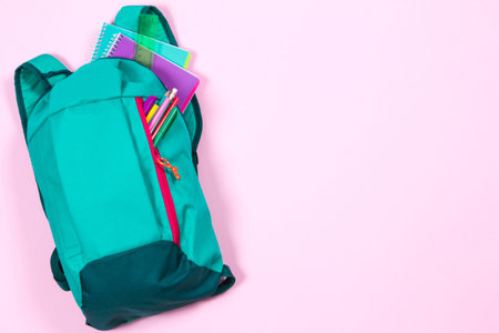 Backpack with school stationery and apple on pink backgroundの写真素材
