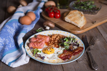 Fried eggs with bacon, sausages and beans in tomato sauce