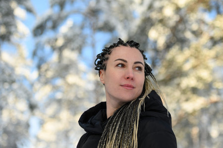 woman with African braids and a hood smiling and looking to the sideの写真素材