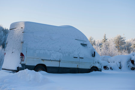White minibus covered with thick layer of snow in the fieldの写真素材