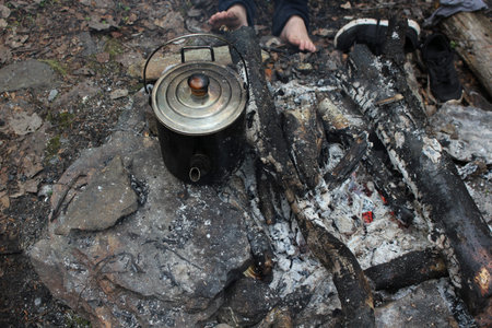 Campfire in the wild forest. Smoked kettle boiling on a fire Â 
