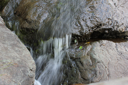  Mountain waterfall. Mountain river among gray huge boulders in the middle of a dense forest next to...